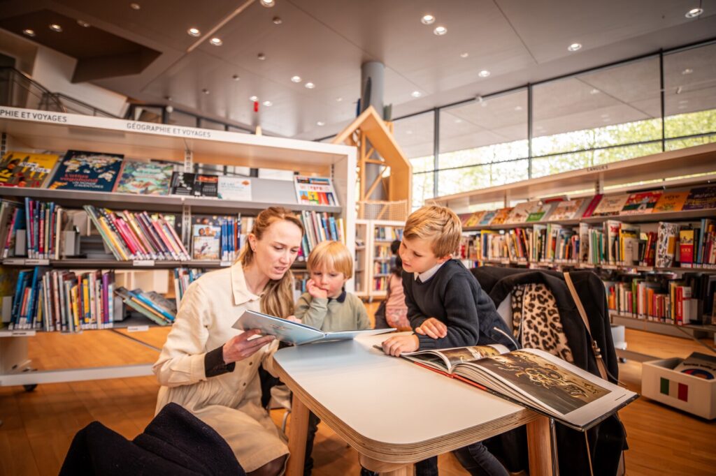 Une maman et ses enfants lisent des livres à la bibliothèque des Champs Libres