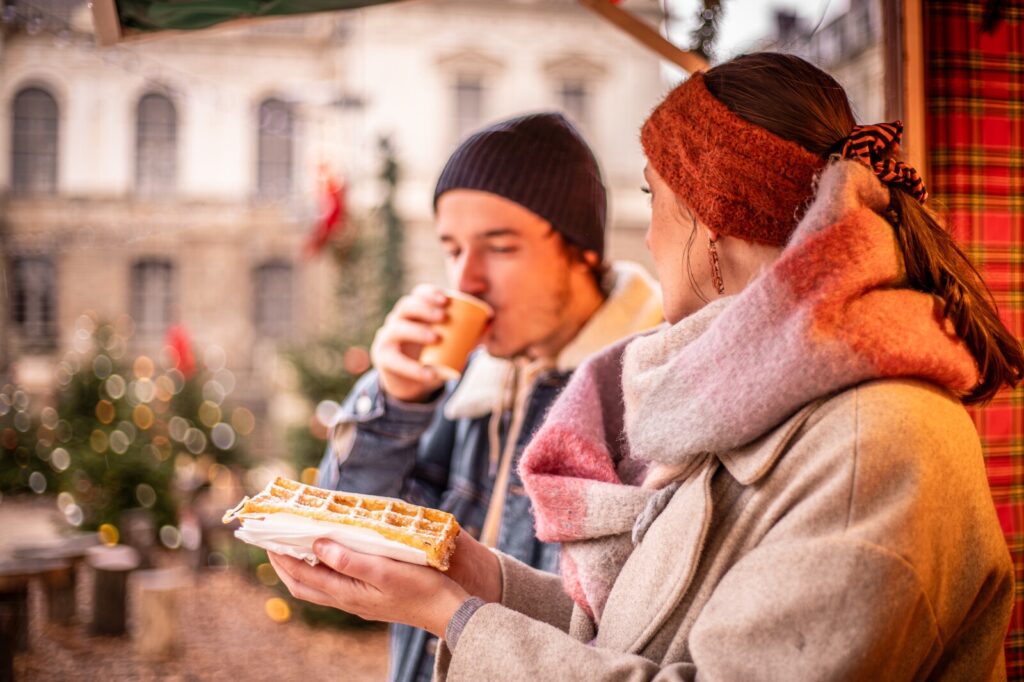 Un couple déguste une gauffre au marché de Noël place du Parlement de Bretagne