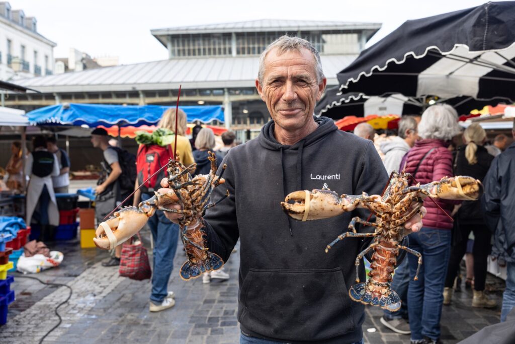 Un producteur présente deux beaux homards sur le Marché des Lices