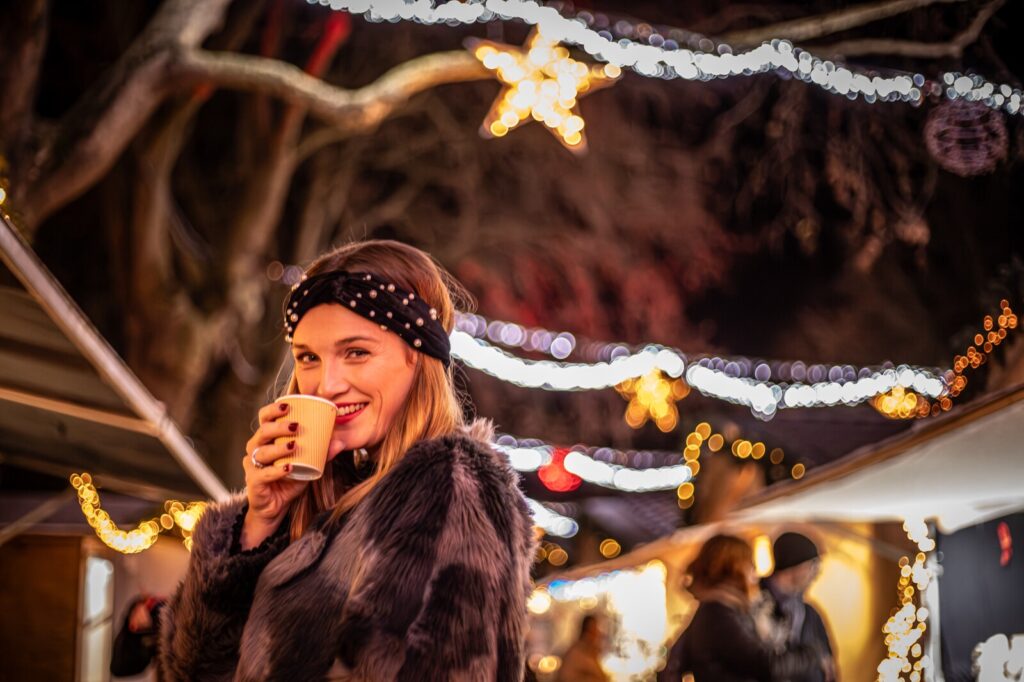 Une femme boit une boisson chaude au marché de Noël du Mail