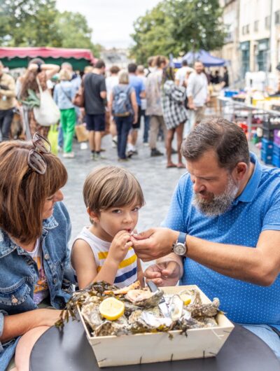 Une famille déguste des huîtres sur une terrasse au coeur du marché des Lices à Rennes en Bretagne