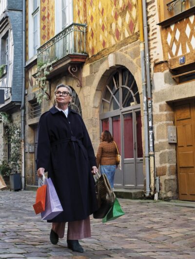 Une femme flâne dans les rues commerçantes et piétonnes du vieux Rennes