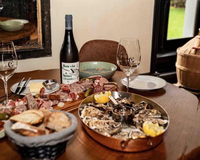 Table avec planche de charcuteries, plateau de fruits de mer et bouteille de vin.