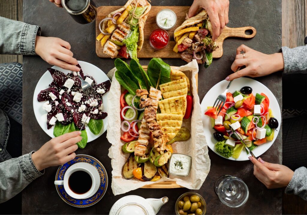 Vue de haut d'une table de restaurant avec des spécialités grecques que se partagent deux convives.