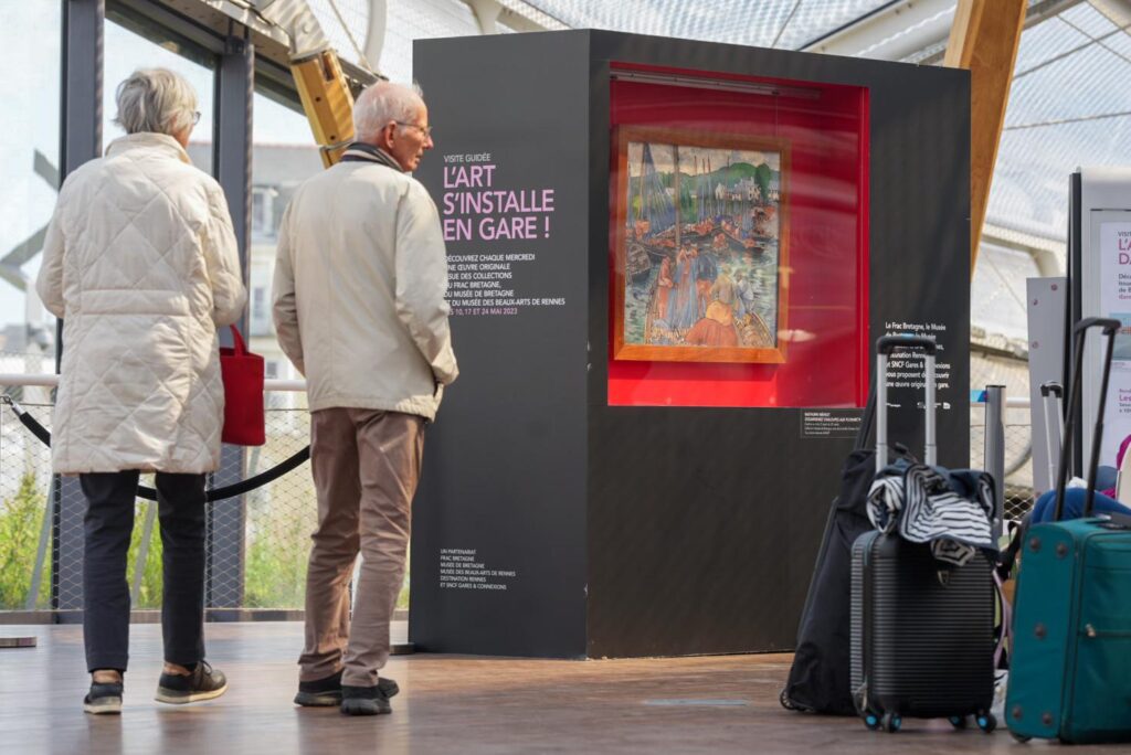 Deux personnes à la gare de Rennes devant un tableau, dans le cadre d'Un jour, une oeuvre