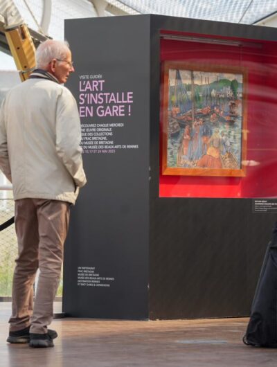 Deux personnes à la gare de Rennes devant un tableau, dans le cadre d'Un jour, une oeuvre