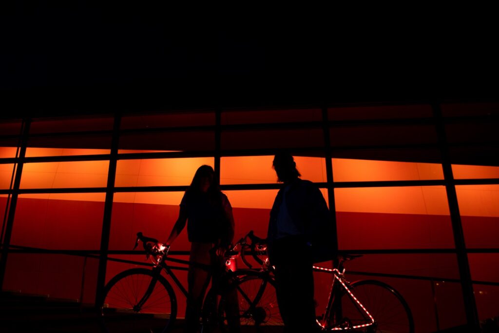 Un couple de cyclotouristes au soleil couchant devant le bâtiment du Frac Bretagne à Rennes.